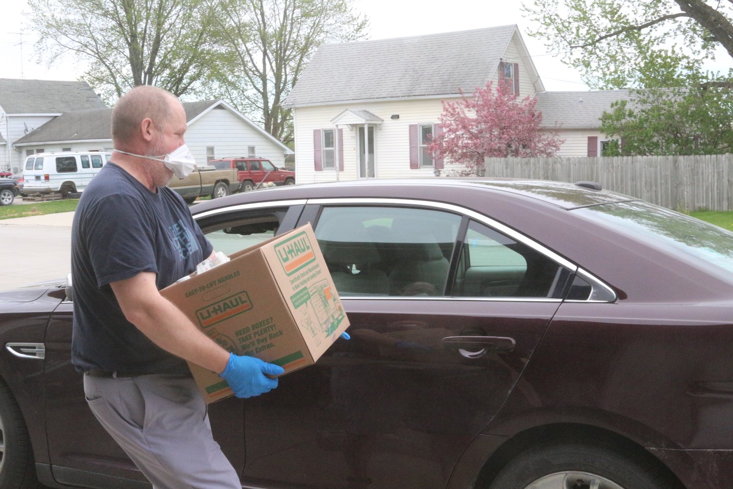 Kalona City Administrator Ryan Schlabaugh carries a box of food to a car.